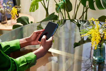 Cropped view of entrepreneur using mobile phone at workplace