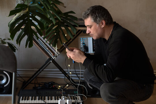 Musician in his studio texting on the smartphone