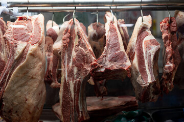 Variety of meat cuts hanging from hooks at buchery (small business)