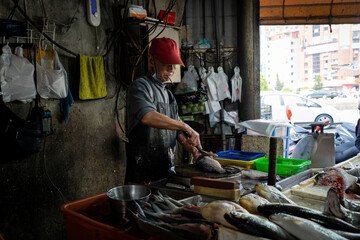 A vendor smokes a cigarette while chopping fish in Taiwan