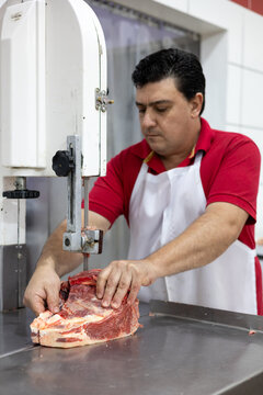 Butcher slicing portion of fresh meat for his customers at the shop