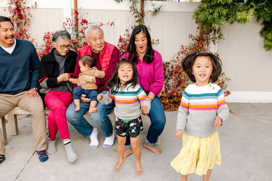 Smiling asian family with grandparents sitting outdoors together 