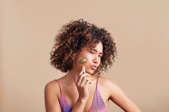 Woman pouting lips while using jade roller