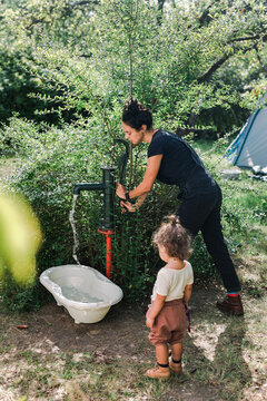Mother and Daughter Pumping Water in the tub in the Garden