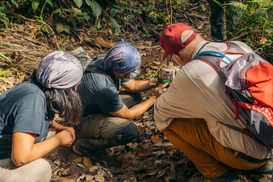Two men and one woman setting a camera trap in nature