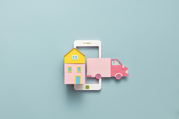 House and truck made of colorful paper on smartphone mockup.
