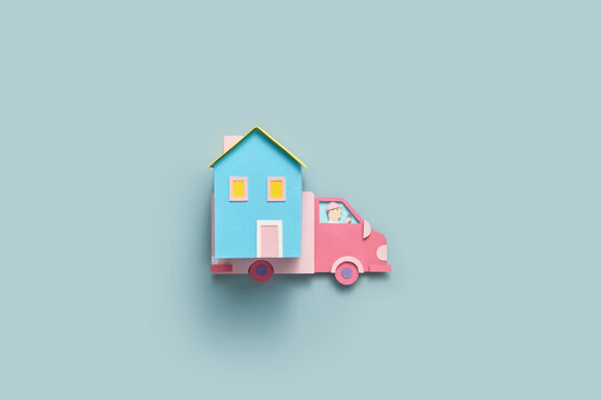 Blue papercraft house being transported on pink paper truck.