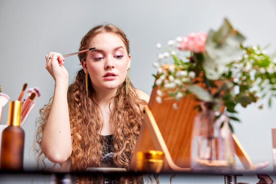 Young woman applying makeup near mirror