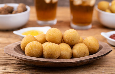 Typical brazilian snack cheese ball on a plate with soda glass, ketchup and mustard