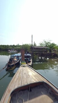 Vertical video 4k. Aerial low dynamic view flying over calm river surface green trees forest with village harbor port Asian fishing boat. FPV sport drone shot tropical pond rustic house nature lush
