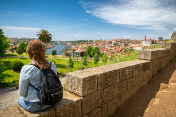 Fototapeta na wymiar Girl enjoying panoramic view of city landscape, famous bridge and Douro river of Oporto- Portugal. Porto travel destination, magazine concept, selective focus