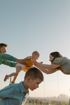 Dad Passes Daughter to Mom with Son in Foreground