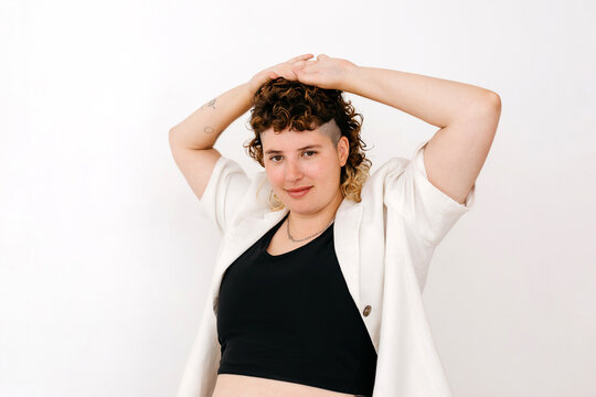 Content non binary person with hands up in studio