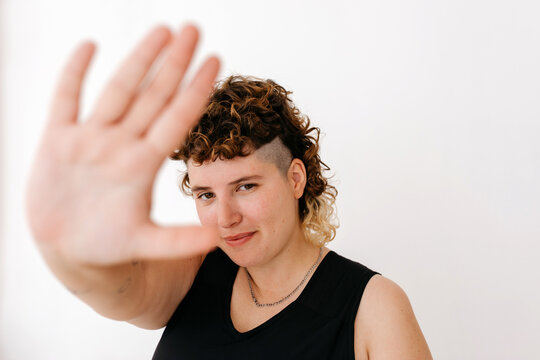 Smiling queer person showing stop gesture in studio