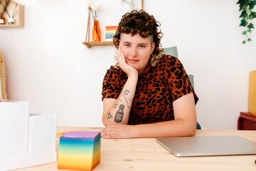 Smiling non binary person with tattoos sitting at table