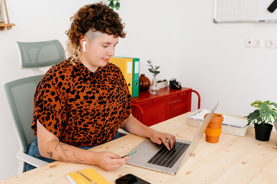 Calm non binary person with credit card and laptop