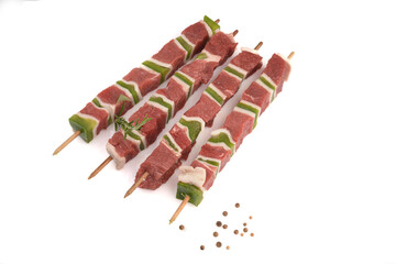 quatres brochettes de boeuf cru sur fond blanc