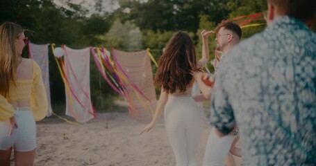 Young couple dancing bachata while surrounded by friends at beach