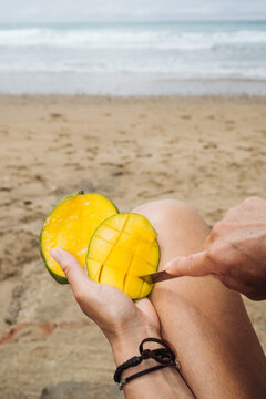 Cutting mango on the beach