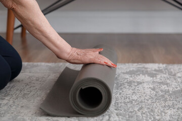 Crop woman with yoga mat in room