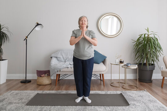 Calm aged woman practicing yoga with hands in namaste