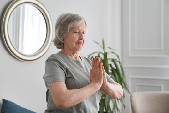Senior woman meditating in light living room