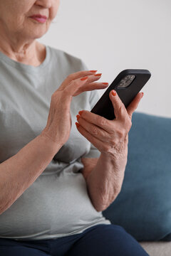 Crop woman with smartphone on sofa