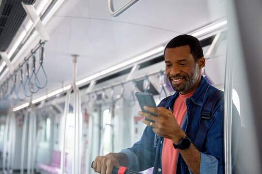 Man using mobile phone while traveling in a metro with push scooter