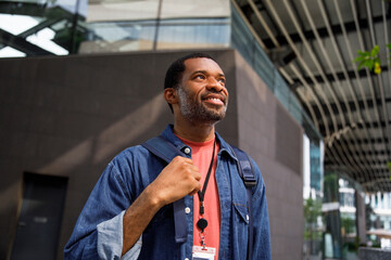Smiling man carrying backpack in city going to office 