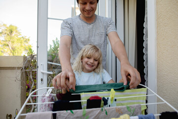 Father with daughter doing laundry on the balcony