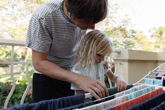 Father with daughter doing hanging clothes on the balcony 