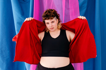 Confident plump non binary person putting on red shirt