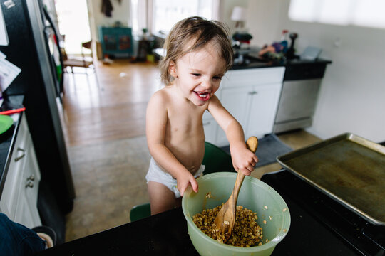 Toddler mixes ingredients while cooking in kitchen