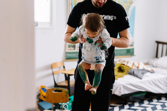 Dad carries toddler covered in paint out of room 
