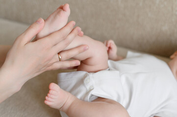 Fototapeta na wymiar Mom massages the baby legs. Children massage.The concept of babysitting,maternity leave,masseur.Prevention of flat feet