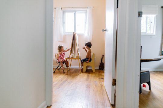 Siblings paint at easel