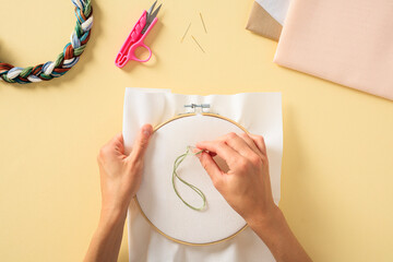 Embroidery needlework concept. Colorful threads and embroidery hoop with fabric in female hands.