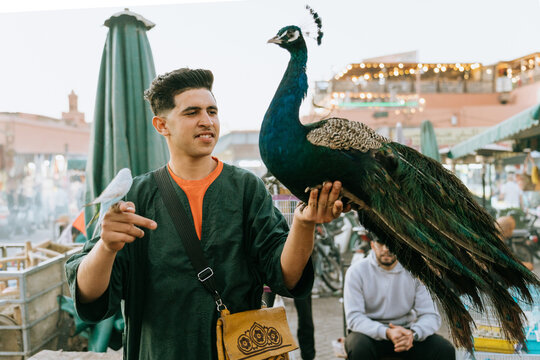 Street performer holding birds in a market