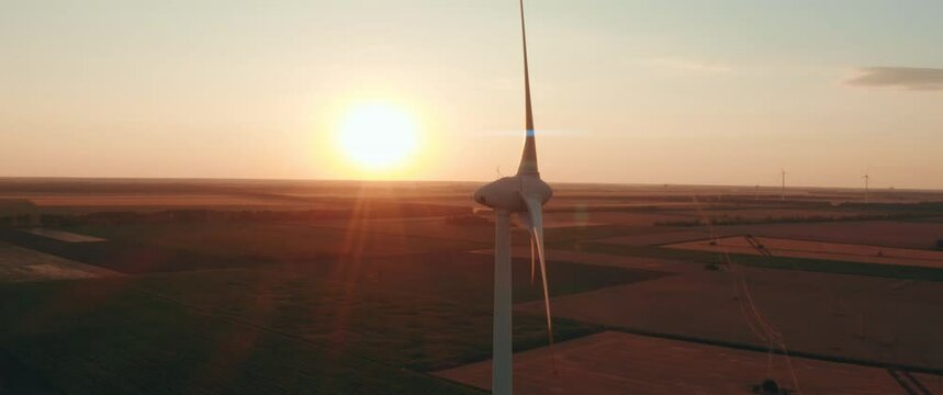 Scenic Aerial view of wind turbines farm in sunset time. Anamorphic 1.33 footage with lens flares