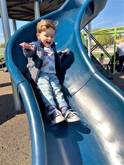 Action shot of toddler boy having fun going down a blue sliding board. © Caroline