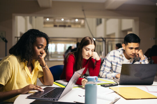 Students doing work and studying with laptops and notes in the college