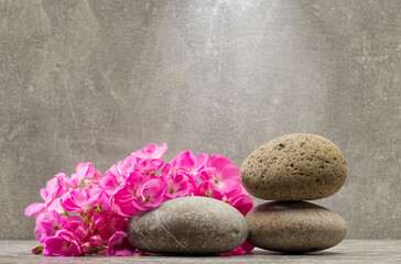 Fototapeta na wymiar gray zen stones and pink flowers on a gray background for product presentation podium background