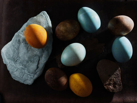 colorful  painted easter eggs and stones on a brown dark background