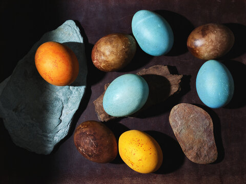 colorful  painted easter eggs and stones on a brown dark background