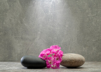 Fototapeta na wymiar gray zen stones and pink flowers on a gray background for product presentation podium background