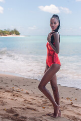 Portrait of Beautiful Caribbean Adult Teen in Barbados. Wearing Red Bikini and Standing on a tropical beach. Caribbean Sea in Background. Black. Portrait.