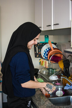 Happy muslim person washing dishes in the kitchen