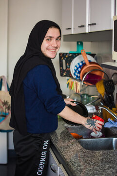 Happy transgender person doing chores in the kitchen