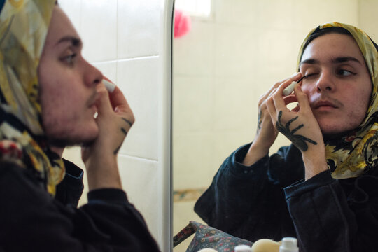Queer person applying make up