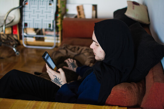 Muslim person using phone while sitting in the sofa